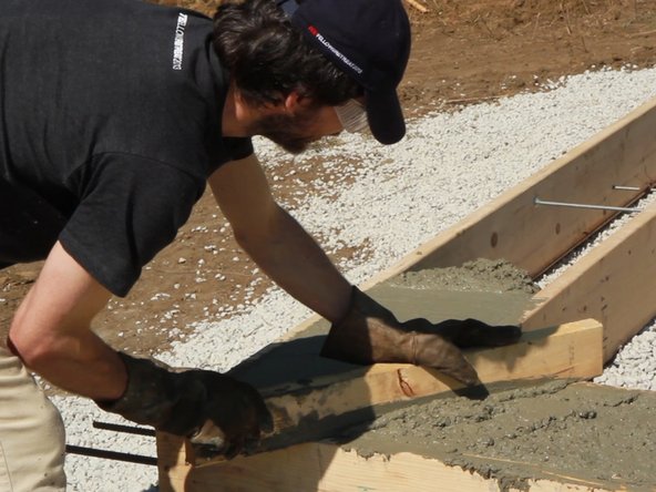 Pour concrete into foundation forms. Fill the foundation forms with concrete and smooth off the top with a screed board. We had a truck deliver the concrete, but you could also mix it yourself in a concrete mixer or in a wheelbarrow with a mixing hoe.