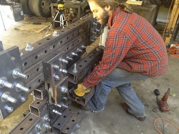 Put the table assembly threaded rods through the frame from the side with the lower blade. They should go through the holes on either side of the lower blade plate.