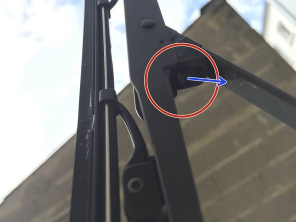 Appuyez sur la languette située en dessous du balais (flèche)