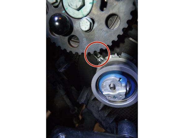 Insérer le nouveau galet tendeur en prenant soin de le positionner correctement. L'index pointé en rouge doit rentrer dans le carter. Insérer la goupille de blocage et détendre le galet tendeur à fond comme cela a été fait pour la dépose.