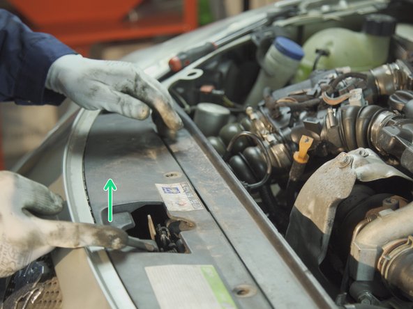 Une fois toutes les agrafes retirées, actionner le crochet d'ouverture du capot pour faire passer le pare-choc