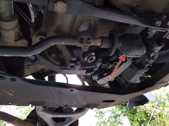 Sous la voiture, enlever le caoutchouc de protection pour accéder à la vis qui tient la commande de vitesse.