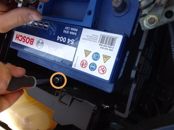 Déposer la bride de fixation de la batterie, tournevis avec rallonge et douille de 13