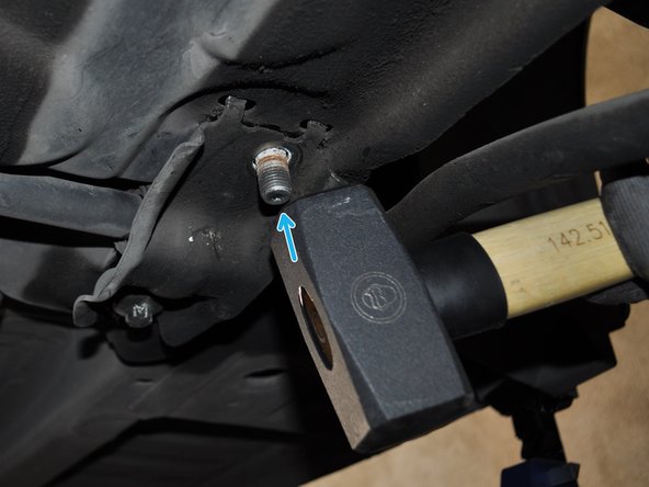 Taper légèrement sur la vis pour la faire remonter mais sans la sortir de son logement car elle maintient une partie du triangle de suspension.