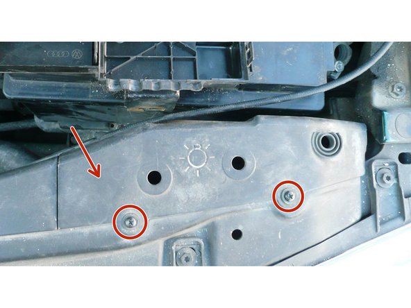 Dévisser le cache plastique noir en coté phare de la batterie avec un tournevis cruciforme.