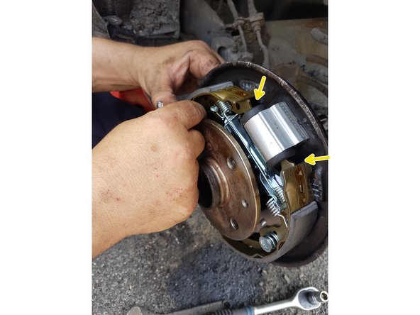 Fixez les garnitures au tambour avec les rivets et ressorts neufs, en compressant le ressort et en pivotant le rivet pour le bloquer.