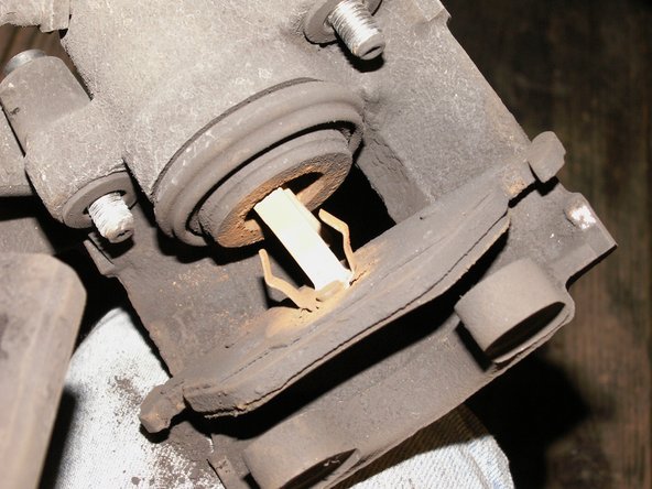 Retirer la plaquette arrière avec un tournevis plat car elle est maintenue par un clip ressort en acier. Prenez garde à ne pas toucher le soufflet caoutchouc de protection du piston.