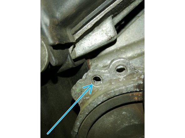 Détendre le galet tendeur à l'aide d'une clef de 15 en agissant sur le boulon au centre du galet (cercle orange)