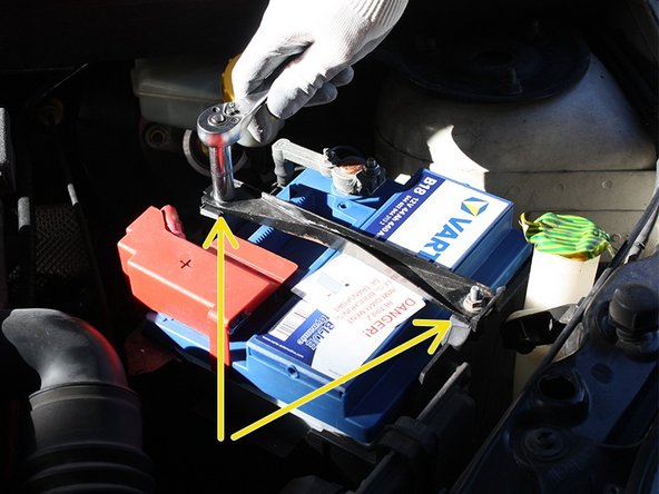 A l'aide d'une clé à cliquet avec douille de 10, dévisser les deux écrous qui retiennent la bride de fixation de batterie, récupérer les écrous en veillant à ne pas les faire tomber.