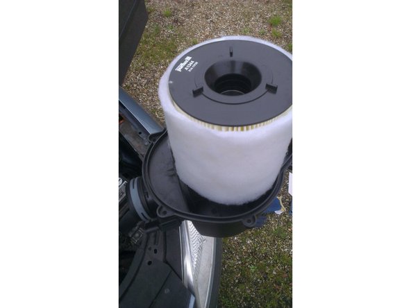 Une fois les encoches en face des logements, il faut tourner le filtre sur lui même, afin que les encoches assurent la fixation du filtre sur le capot de la boite à air.