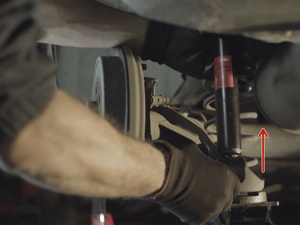 Compresser légèrement l'amortisseur pour faire passer le bas dans son emplacement