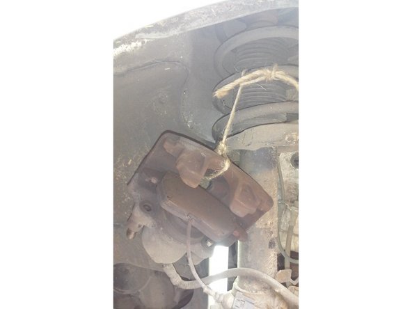 Avec une ficelle ou fil de fer attacher l'étrier de frein au ressort de l'amortisseur.