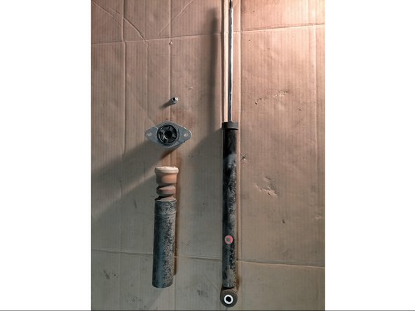 On voit ici l'amortisseur, le cache poussières, la butée en caoutchouc, l'étrier et l'écrou.