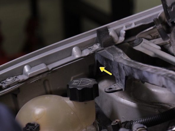 Replacer la traverse en plastique,l’insérer dans l'encoche  coté passager et visser la partie de la barre coté conducteur