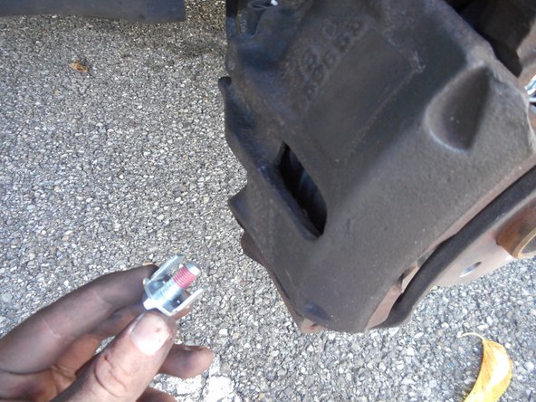 Replacez la vis de colonnette en s'assurant que les ergots soient bien alignés par rapport au support d'étrier, puis la visser à l'aide d'un cliquet et d'une douille de 13mm