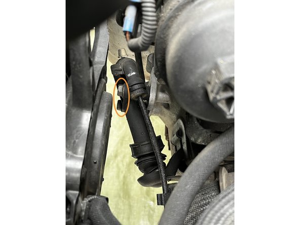 Sous le véhicule, dévisser la deuxième vis du support de câble a l'aide d'une clé de 13 et dégager le support de câble.
