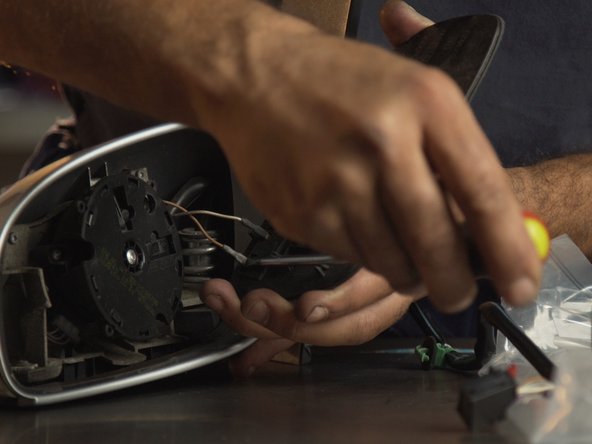 Avec un petit tournevis plat, détacher les deux connecteurs du miroir