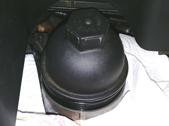 A l'aide d'un cliquet, d'une rallonge et d'une douille de 32, desserrer la filtre à huile sans le sortir