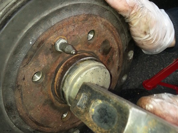Remettre en place le cache d'écrou de l'axe, en tapotant avec un marteau sur le pourtour en tournant
