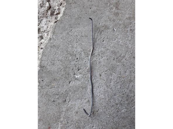 En utilisant le bout de cintre tordu comme sur la photo.