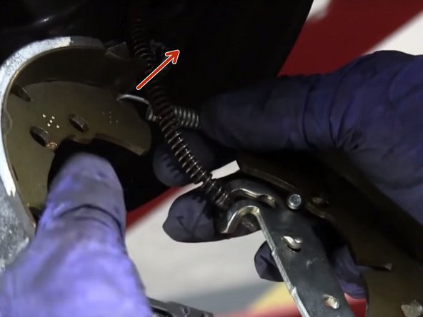 Desserrer le ressort du kit de frein puis le faire passer devant le câble de frein à main et le raccrocher