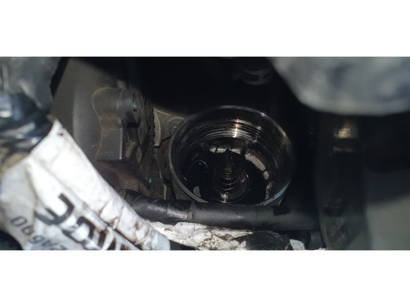 Protéger à l'aide d'un chiffon et retirer le couvercle du boitier de filtre à huile le filtre viendra avec celui-ci.