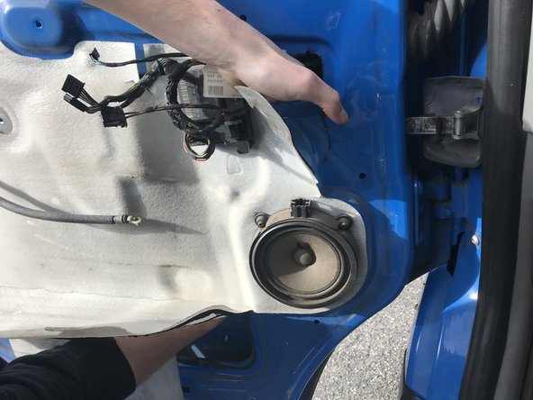 Dévisser la vis présente derrière l'isolant de la porte à l'aide d'un cliquet ou d'un tournevis porte embouts équipé d'un embout Torx T20 tout en maintenant le cale porte par l'ouverture présente au dessus de la vis.