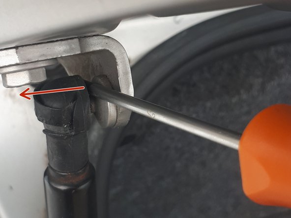 Faire glisser le clip métallique de l'attache du vérin vers le haut afin de libérer l'attache en faisant levier avec un tournevis.