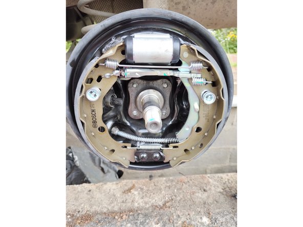 Poser le câble de frein dans son logement, enlever l'écarteur en plastique et remonter les mâchoires en commençant par le bas puis le haut et en faisant attention de ne pas abimer les joints de cylindre