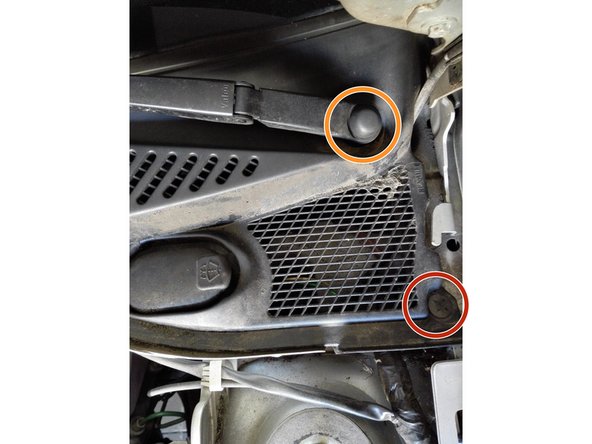 A l'aide d'un tournevis plat, soulever délicatement le clip entouré en rouge. Ce clip fixe la grille en plastique à la carrosserie.