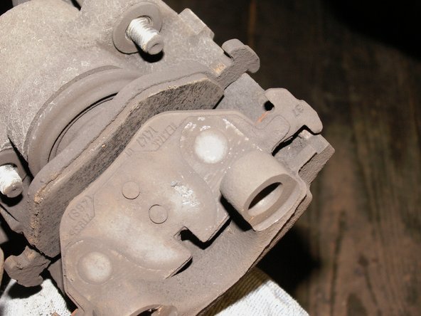 Retirer la plaquette arrière avec un tournevis plat car elle est maintenue par un clip ressort en acier. Prenez garde à ne pas toucher le soufflet caoutchouc de protection du piston.