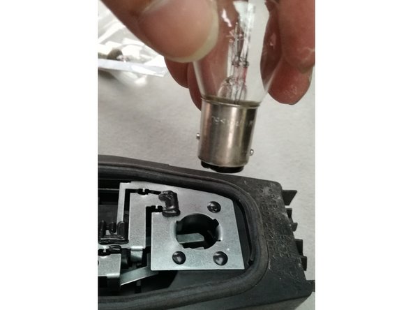 remplacement par la nouvelle ampoule, insérée dans son logement et tournée d'un quart de tour tout en la maintenant enfoncée