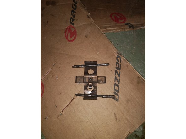 Il y a deux goupilles de maintient des plaquettes sur votre étrier. Une supérieure et une inférieure. Les chasser avec un chasse goupille ou un petit tournevis. Les deux goupilles sont identiques, pas de soucis si vous les mélangez. Une fois les deux goupilles retirées, l'agrafe de maintient est libérée. Conservez bien ces trois éléments.