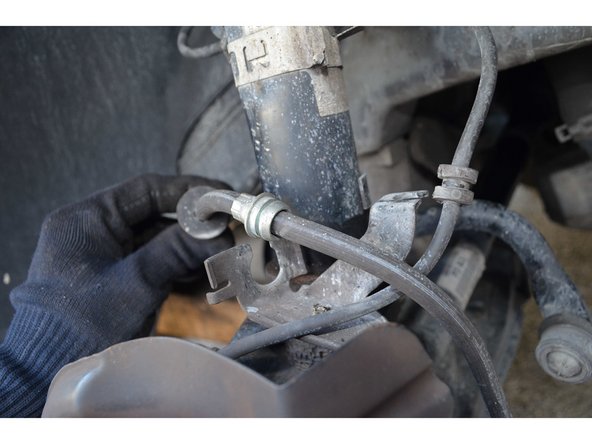 Le flexible de frein est maintenu par une agrafe. Avec un petit tournevis plat retirez l'agrafe puis dégagez le flexible.