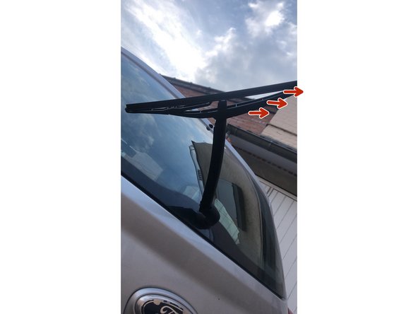 Maintenir le bras et pousser l'essui glace dans le sens des flèches