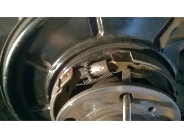 Décrocher le ressort de rappel supérieur avec une pince ou un tournevis et déposer le dispositif de rattrapage.