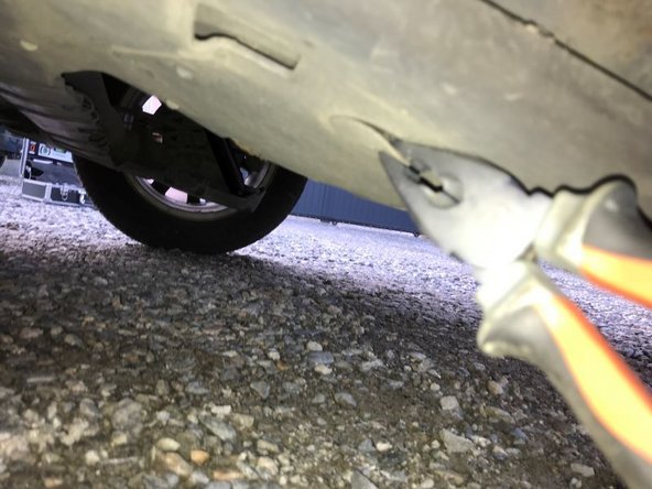 Il faut déposer la protection de l'amortisseur en enlevant le clips plastique et en dévissant le boulon à l'aide d'un cliquet et une douille de 10