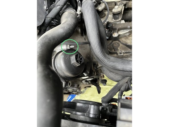 Dévisser et déposer la vis de fixation de boite a l'avant du compartiment moteur a l'aide d'une clé de 13.