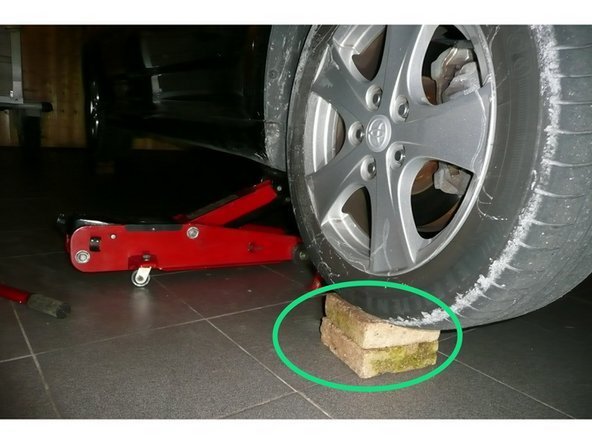 Lever une première roue à l'aide d'un cric rouleur et placer une cale Hauteur 15 cm sous la roue après avoir serré le frein à main et enclenché la 1ʳᵉ vitesse.