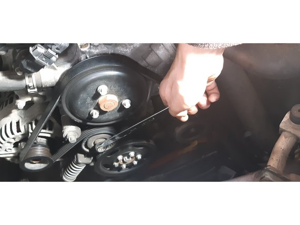 placer une clé de 14 sur l'écrou du galet tendeur et serrer pour détendre le galet et retirer la courroie