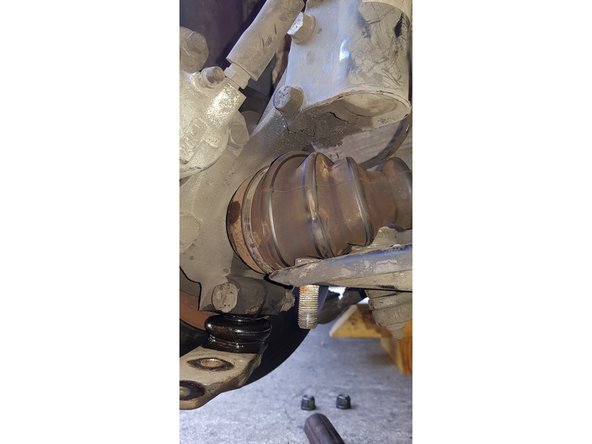 Avec une douille et une clé mixte de 18mm, retirez les 2 écrous ainsi que la vis côté intérieur puis désaccouplez la rotule du triangle.