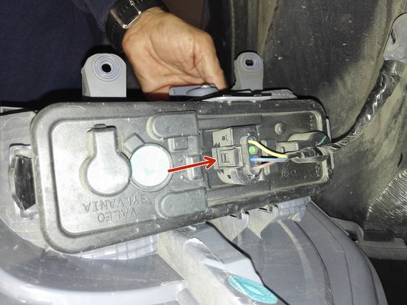 Photo 1: on clipe l'alimentation électrique sur la platine (flèche rouge) avant de replacer l'optique dans son logement sur l'aile arrière droite.