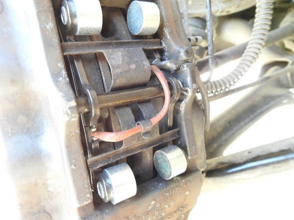 Il faut mettre en place le contacteur de témoin d’usure neuf, on ne peut pas se tromper, ils ne rentrent que dans un sens, juste penser à mettre la prise du bon côté sinon ça sera un peu juste en longueur. On remet la plaque dans le bon sens (patte pour le fil du contacteur en bas), on remet l’axe et non n’oublie pas de remette la goupille.