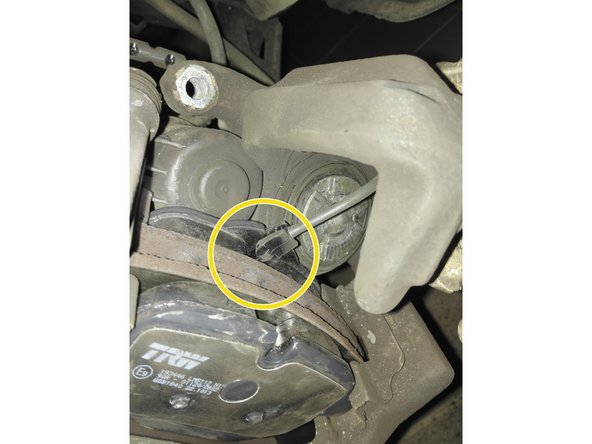 Photo 3: On peut alors insérer les plaquettes neuves dans l'étrier. On fait passer le câble de témoin d'usure dans la mâchoire d'étrier pour le fixer sur la plaquette intérieure.(cercle jaune)