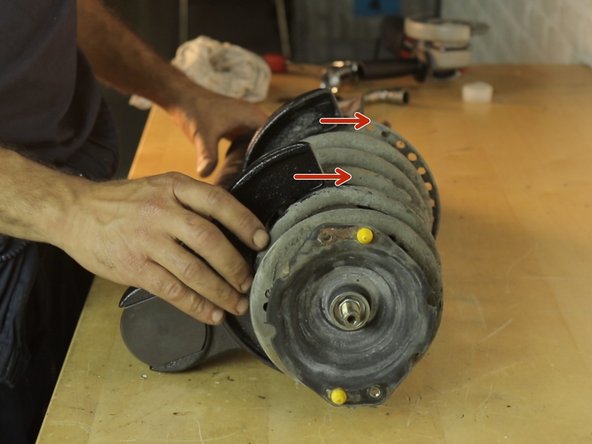 Placer l'amortisseur sur l'établi, puis installer le compresseur de ressort sur les spires les plus proches de l’extrémité