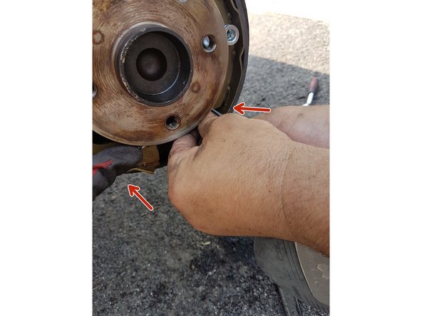 Avec une pince, raccrochez le ressort inférieur aux deux extrémités basses des garnitures des freins.