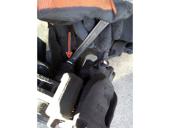 Dévissez les deux vis de la patte de fixation inférieure derrière l'étrier à l'aide d'une clé de 15.