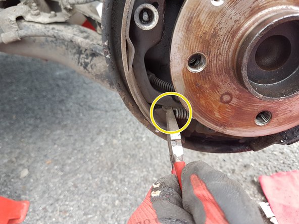 Déloger le ressort de rappel inférieur avec une pince.