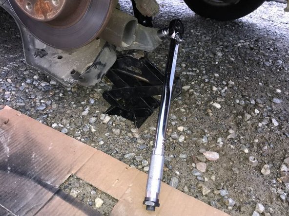 Finir de serrer l'écrou et le boulon inférieur de l'amortisseur puis enlever le cric et remettre la protection de l'amortisseur et le fixer avec le clips et le boulon.