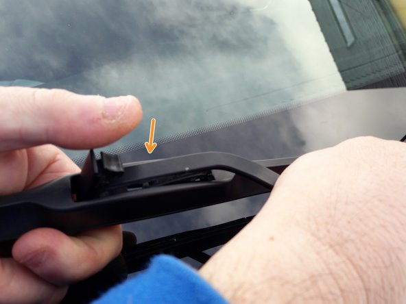 Afin de repositionner le balai d'essuie-glace, d'une main tenir le balai, de l'autre saisir le bras. Placer la pâte du bras au dessus de l'encoche du balai